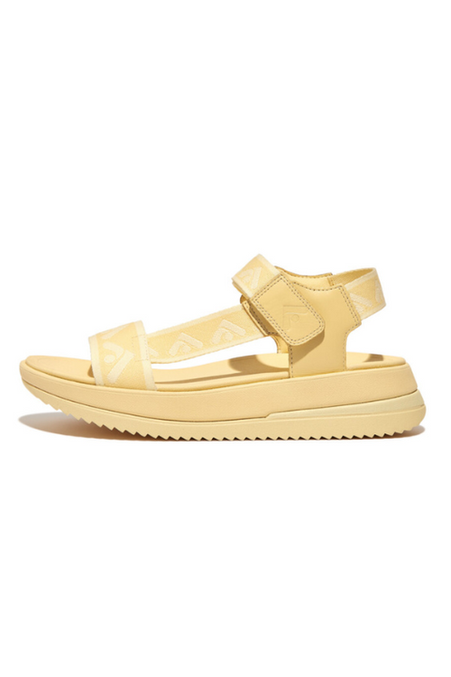 Fitflop Surff Webbing Back Strap Sandals. A pair of yellow chunky sandals with wide strap featuring an arrow print design and microwobbleboard cushioned sole.