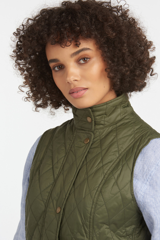 An image of a female model wearing the Barbour Otterburn Gilet in the colour Olive.