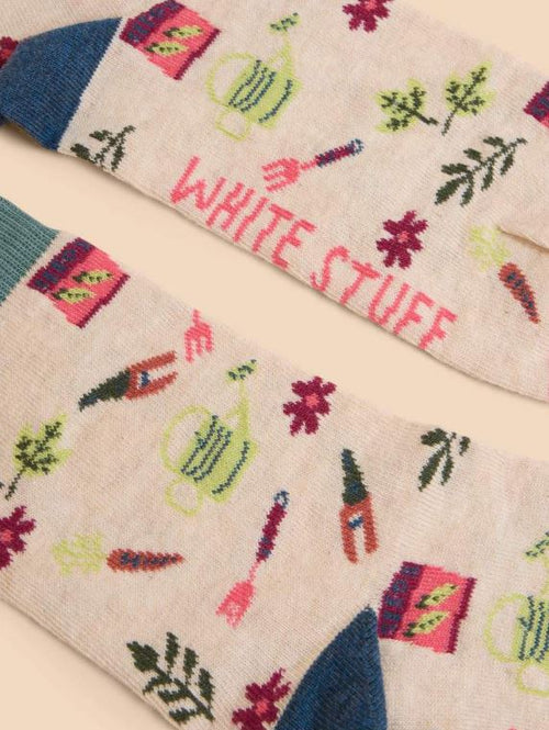 White Stuff Gardening Sock. A cream sock with a colourful design of multiple gardening tools all-over.