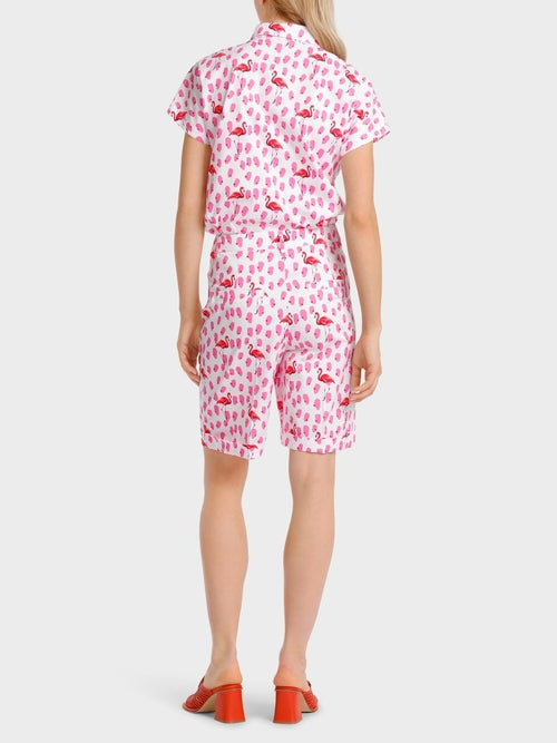 Marc Cain Flamingo Short Sleeve Blouse. An oversized fit blouse with kimono sleeves, Kent collar, and button placket. This blouse features a pink flamingo print.