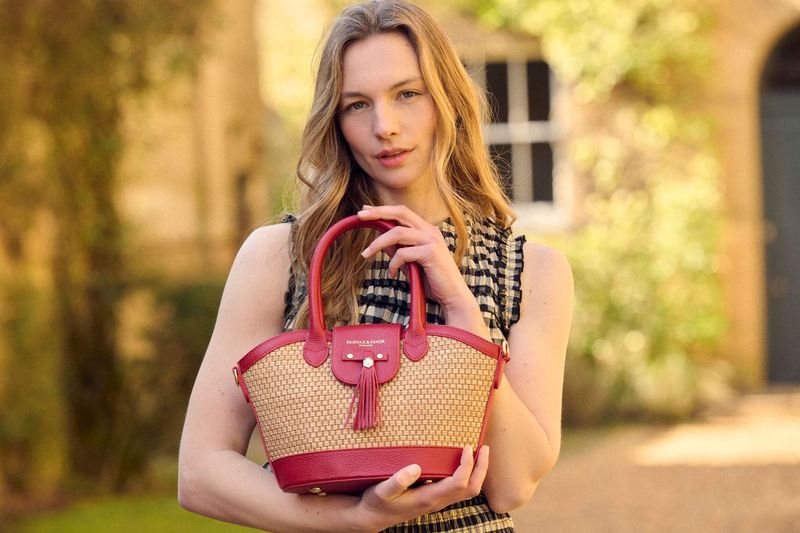 Woman holding a pink and beige handbag outdoors