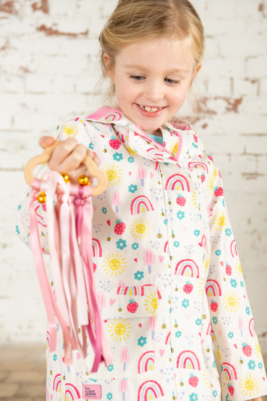 Lighthouse Heidi Jacket. A kids, waterproof coat with a soft jersey lining, and a sweet rainbows & sunshine design on a white background.