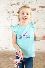 Lighthouse Causeway Swing Tee. A regular fit, kids t-shirt with short ruffle trim sleeves, a crew neck, and a sweet pony design on a light blue background.