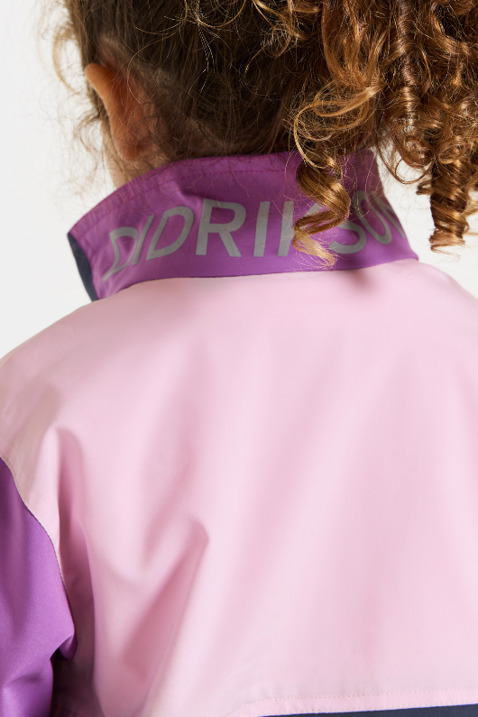 Didriksons Lingon Jacket. A girls windproof jacket in tulip purple with a breathable design, reflective detail, and a water repellent finish