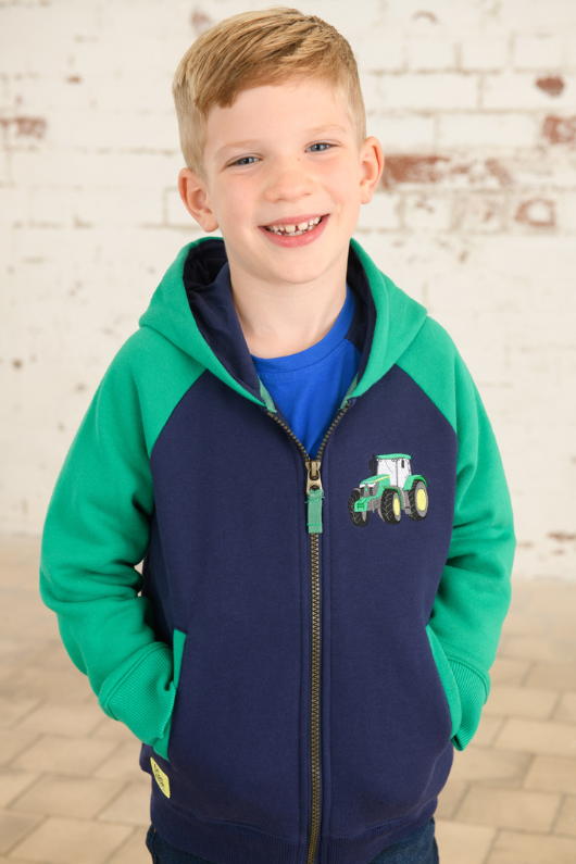 Lighthouse Jackson Full Zip Hoodie. A boys zip-up hoodie with waist pockets, a soft jersey lined hood, and a a navy torso with a tractor piqué on the chest and green sleeves.