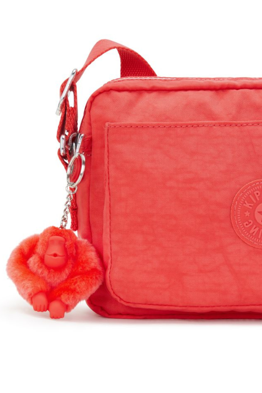 Kipling Abanu Medium Crossbody. A coral crossbody bag with adjustable strap, 2 zipped compartments, multiple pockets, and Kipling logo/monkey charm