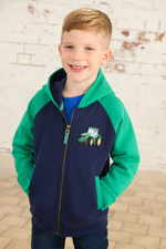 Lighthouse Jackson Full Zip Hoodie. A boys zip-up hoodie with waist pockets, a soft jersey lined hood, and a a navy torso with a tractor piqué on the chest and green sleeves.