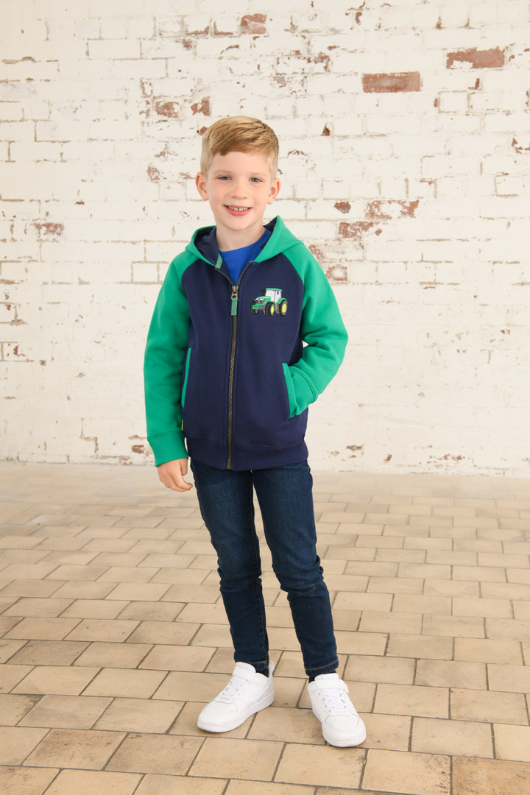 Lighthouse Jackson Full Zip Hoodie. A boys zip-up hoodie with waist pockets, a soft jersey lined hood, and a a navy torso with a tractor piqué on the chest and green sleeves.