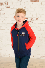 Lighthouse Jackson Full Zip Hoodie. A boys zip-up hoodie with waist pockets, a soft jersey lined hood, and a a navy torso with a tractor piqué on the chest and red sleeves.