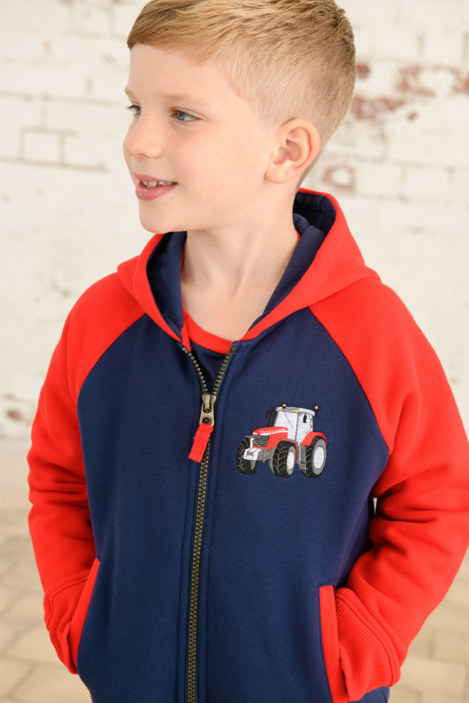 Lighthouse Jackson Full Zip Hoodie. A boys zip-up hoodie with waist pockets, a soft jersey lined hood, and a a navy torso with a tractor piqué on the chest and red sleeves.