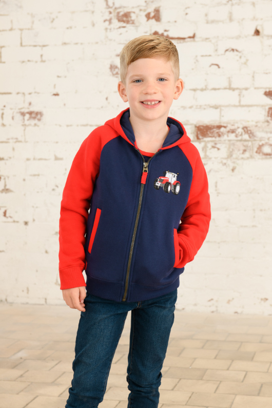 Lighthouse Jackson Full Zip Hoodie. A boys zip-up hoodie with waist pockets, a soft jersey lined hood, and a a navy torso with a tractor piqué on the chest and red sleeves.