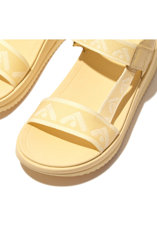 Fitflop Surff Webbing Back Strap Sandals. A pair of yellow chunky sandals with wide strap featuring an arrow print design and microwobbleboard cushioned sole.