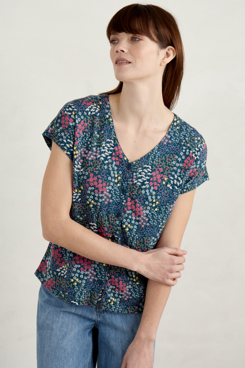 An image of a model wearing the Seasalt Studio Glass V-Neck Jersey Top in the colour Coastal Meadow Light Squid.
