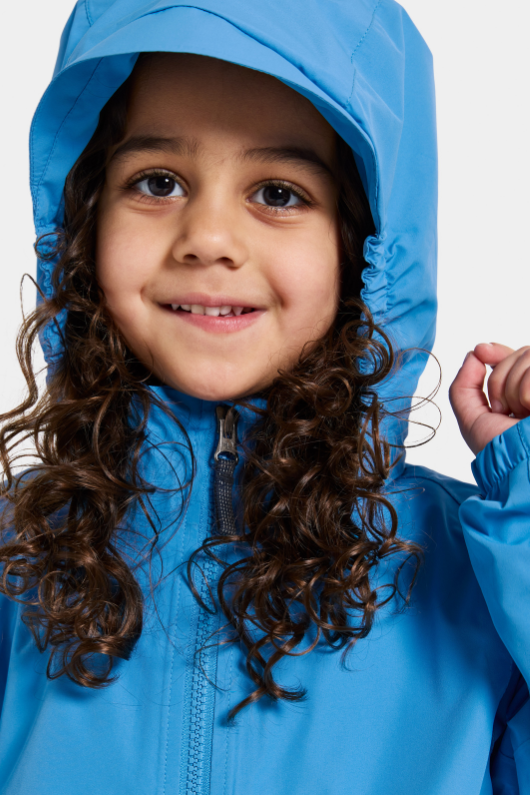 Didriksons Norma Jacket. A windproof kids jacket with a breathable design, a detachable hood, pockets, reflective details on the sleeves and a chin guard
