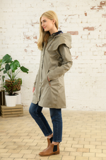 Lighthouse Outrider Waterproof Raincoat. A 3/4 length jacket with a two-way front zip, pockets, a detachable hood with a check lining, and a pale green fawn colour design.