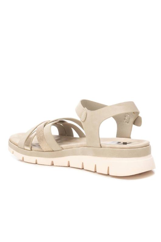 XTI Low Wedge Sandal. A pair of wedge sandals with intertwining metallic gold straps and gold buckle detail.