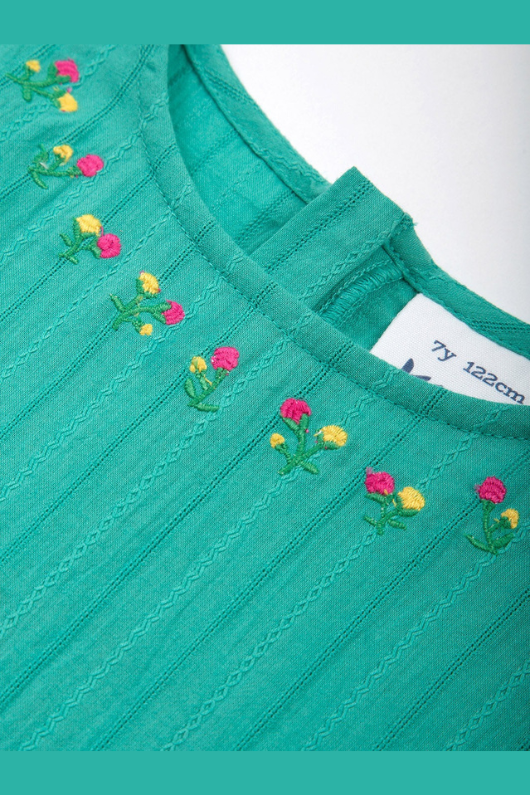 Kite Dress. A green tiered dress with short ruffled sleeves and round neckline featuring floral embroidery.