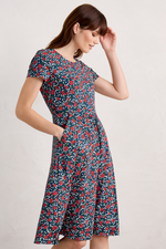 An image of a model wearing the Seasalt April Short Sleeve Dress in the colour Reed Flower Raincloud.