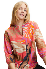 An image of a model wearing the Betty Barclay Leaf Print Tunic-Style Blouse in the colour Red/Beige.