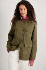 An image of a model wearing the Seasalt Far Horizon Organic Jacket in the colour Laurel.