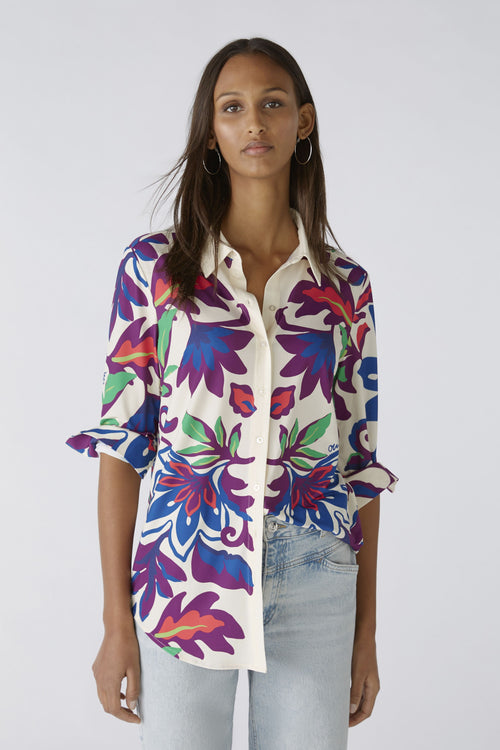 Oui Bold Floral Blouse. A casual cut blouse with long sleeves and collared neckline. This top has a silk touch quality, slightly longer length, and a multicoloured floral print.