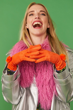 An image of a female model wearing the Jayley Suede Faux Pom Glove in the colour Tangerine.