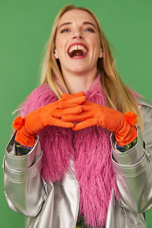 An image of a female model wearing the Jayley Suede Faux Pom Glove in the colour Tangerine.