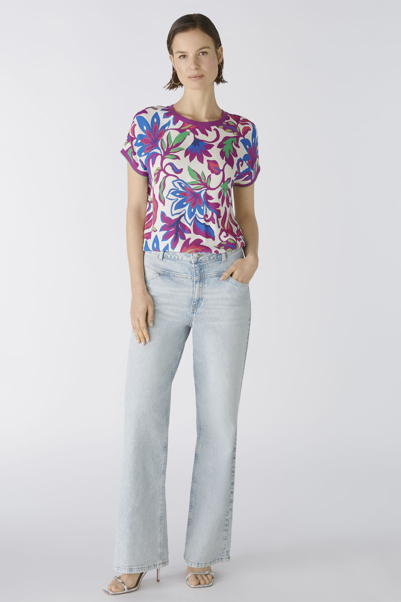 Oui Bottom Floral Blouse. An oversized cut, regular length top with short sleeves and round neckline. The neckline and armholes are a contrasting colour, whilst the front design is floral and the back is striped. This blouse is multicoloured and purple.