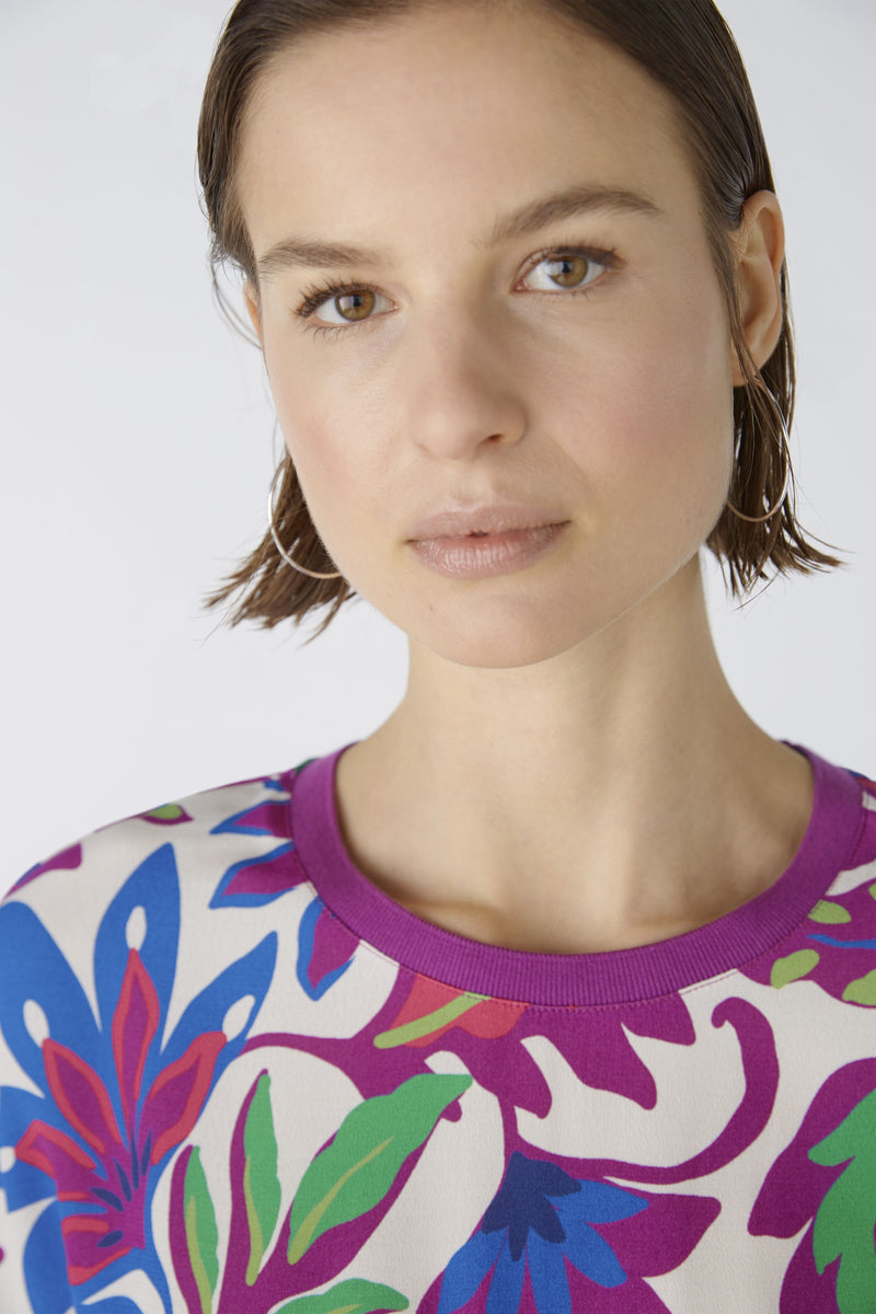 Oui Bottom Floral Blouse. An oversized cut, regular length top with short sleeves and round neckline. The neckline and armholes are a contrasting colour, whilst the front design is floral and the back is striped. This blouse is multicoloured and purple.