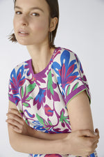 Oui Bottom Floral Blouse. An oversized cut, regular length top with short sleeves and round neckline. The neckline and armholes are a contrasting colour, whilst the front design is floral and the back is striped. This blouse is multicoloured and purple.