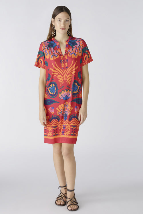 Oui Dress. An above-knee length dress with short sleeves, tunic neckline, and pink/orange all-over print.