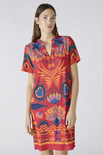 Oui Dress. An above-knee length dress with short sleeves, tunic neckline, and pink/orange all-over print.