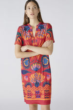 Oui Dress. An above-knee length dress with short sleeves, tunic neckline, and pink/orange all-over print.