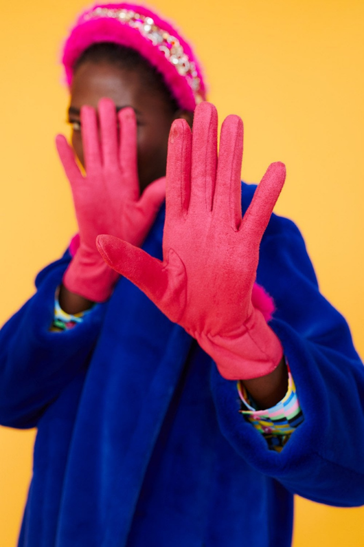 An image of a female model wearing the Jayley Suede Faux Pom Glove in the colour Magenta.