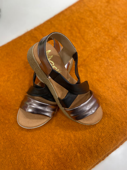 Marila Sling Back Sandal. A pair of low wedge sandals with black cross-over straps and shiny strap.