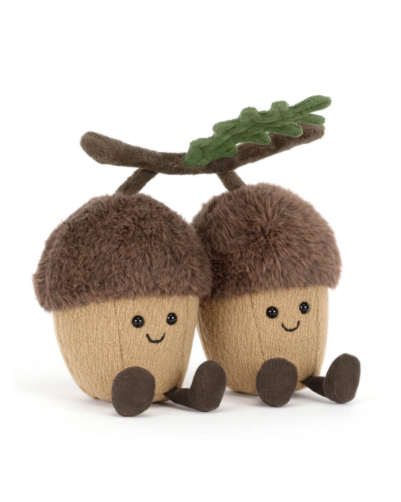 Two plush acorns with faces and a branch on a white background