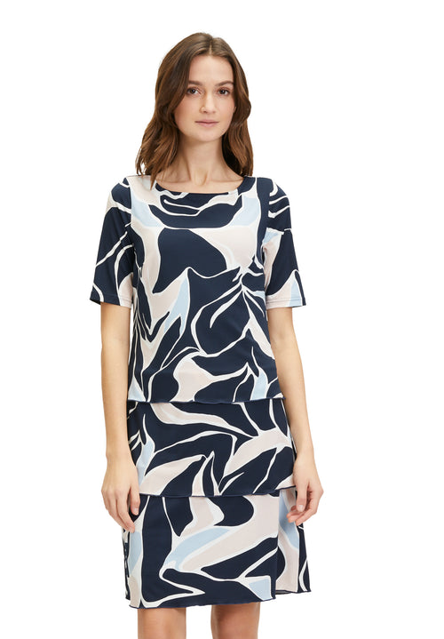 Betty Barclay Tiered Dress. A knee-length straight fit dress, with mid-length sleeves. This dress features an abstract print with pastel blue and pink accents on a navy background.
