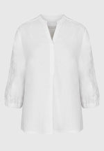 Bianca Linen Adela Blouse. A floaty white blouse with sleeves that fall above the wrist and V-neckline. This blouse also has detailing on the sleeves.