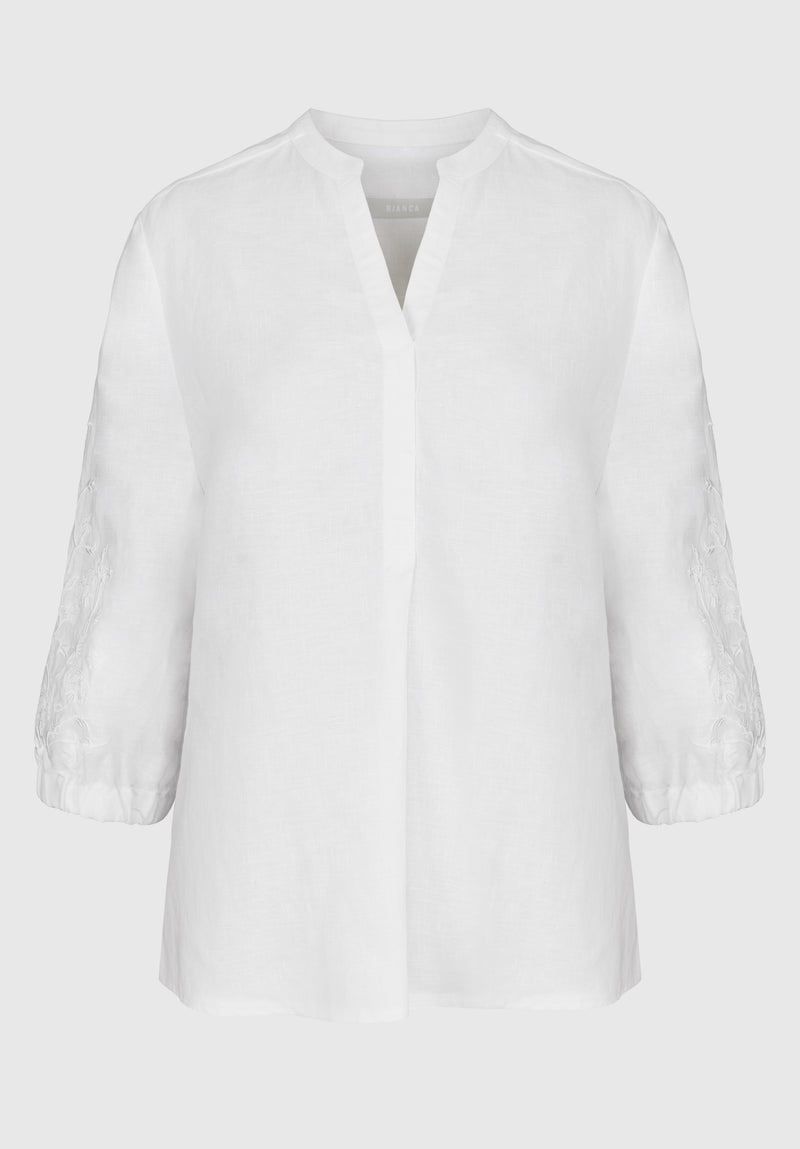 Bianca Linen Adela Blouse. A floaty white blouse with sleeves that fall above the wrist and V-neckline. This blouse also has detailing on the sleeves.