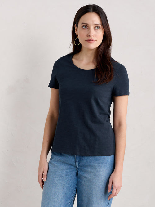 An image of a model wearing the Seasalt Camerance Scoop Neck T-Shirt in the colour Maritime.