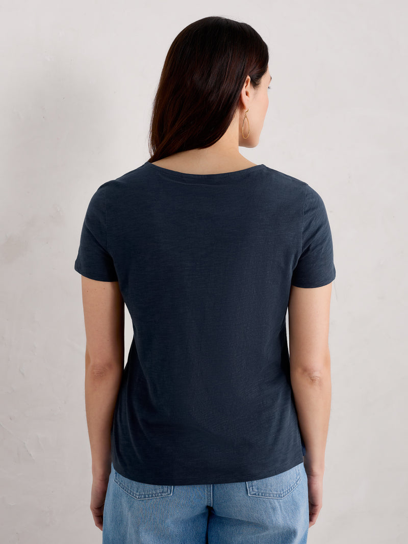 An image of a model wearing the Seasalt Camerance Scoop Neck T-Shirt in the colour Maritime.