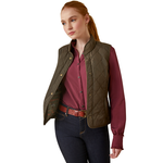 An image of a female model wearing the Ariat Woodside Quilted Gilet in the colour Earth.