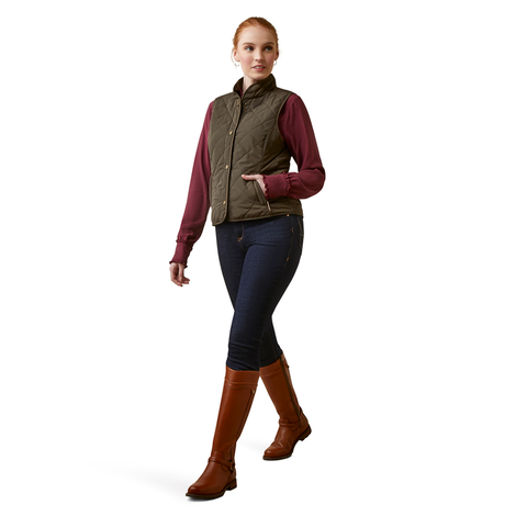 An image of a female model wearing the Ariat Woodside Quilted Gilet in the colour Earth.