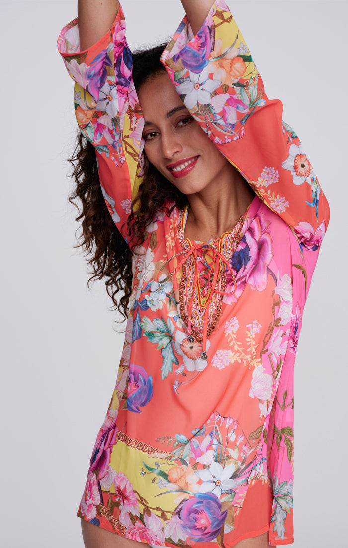 Pia Rossini Hawaii Cover Up. A midi-length, long sleeve cover up in a lightweight material, with V-neckline, dazzling embellishment and pink floral print.