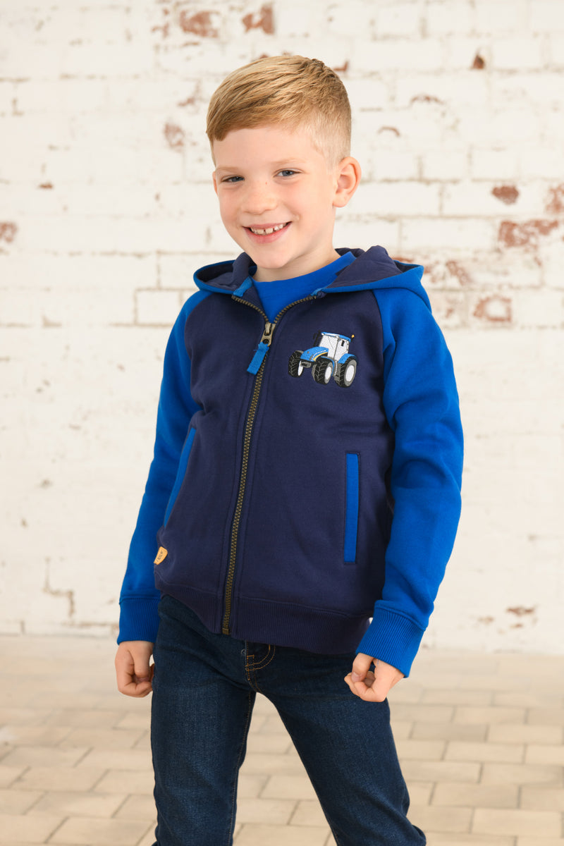 Lighthouse Jackson Full Zip Hoodie. A boys zip-up hoodie with waist pockets, a soft jersey lined hood, and a a navy torso with a tractor piqué on the chest and blue sleeves.