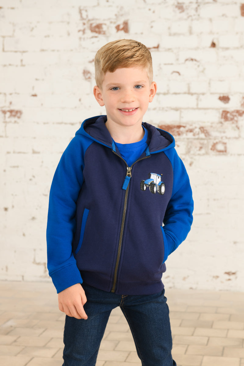 Lighthouse Jackson Full Zip Hoodie. A boys zip-up hoodie with waist pockets, a soft jersey lined hood, and a a navy torso with a tractor piqué on the chest and blue sleeves.