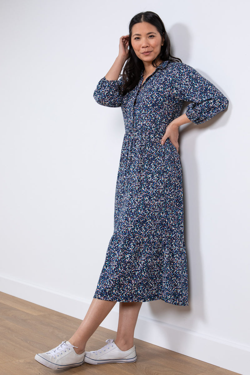 Lily & Me Sadie Terrazzo Dress. A relaxed fit shirt dress with bracelet length sleeves and tiered skirt. This dress has pockets and a navy ditsy print.