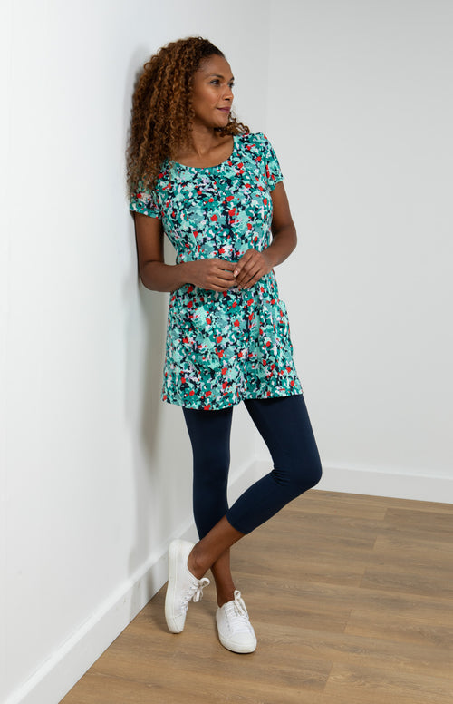Lily & Me Picnic Frieda Tunic. A feminine, cap-sleeved women's tunic with princess seams at the front, front patch pockets, and a bright turquoise design with white, navy and red detail.