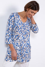 Lily & Me Clover Tunic Confetti. A pretty, women's tunic with 3/4 length sleeves, V-neckline, handy front patch pockets, and a light blue and tan print with white flower detail.