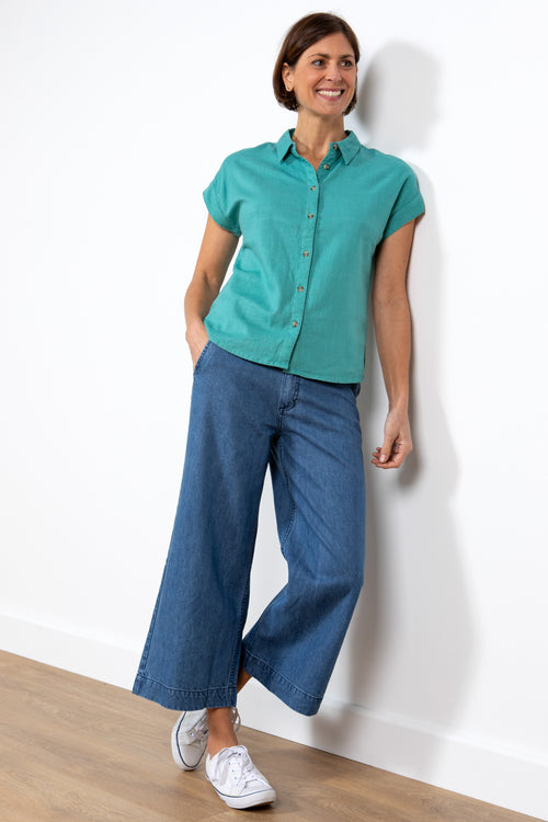 Lily & Me Sky Shirt. A short-sleeved, linen shirt with a button-down front, fixed turn back cuffs, and a plain teal design.